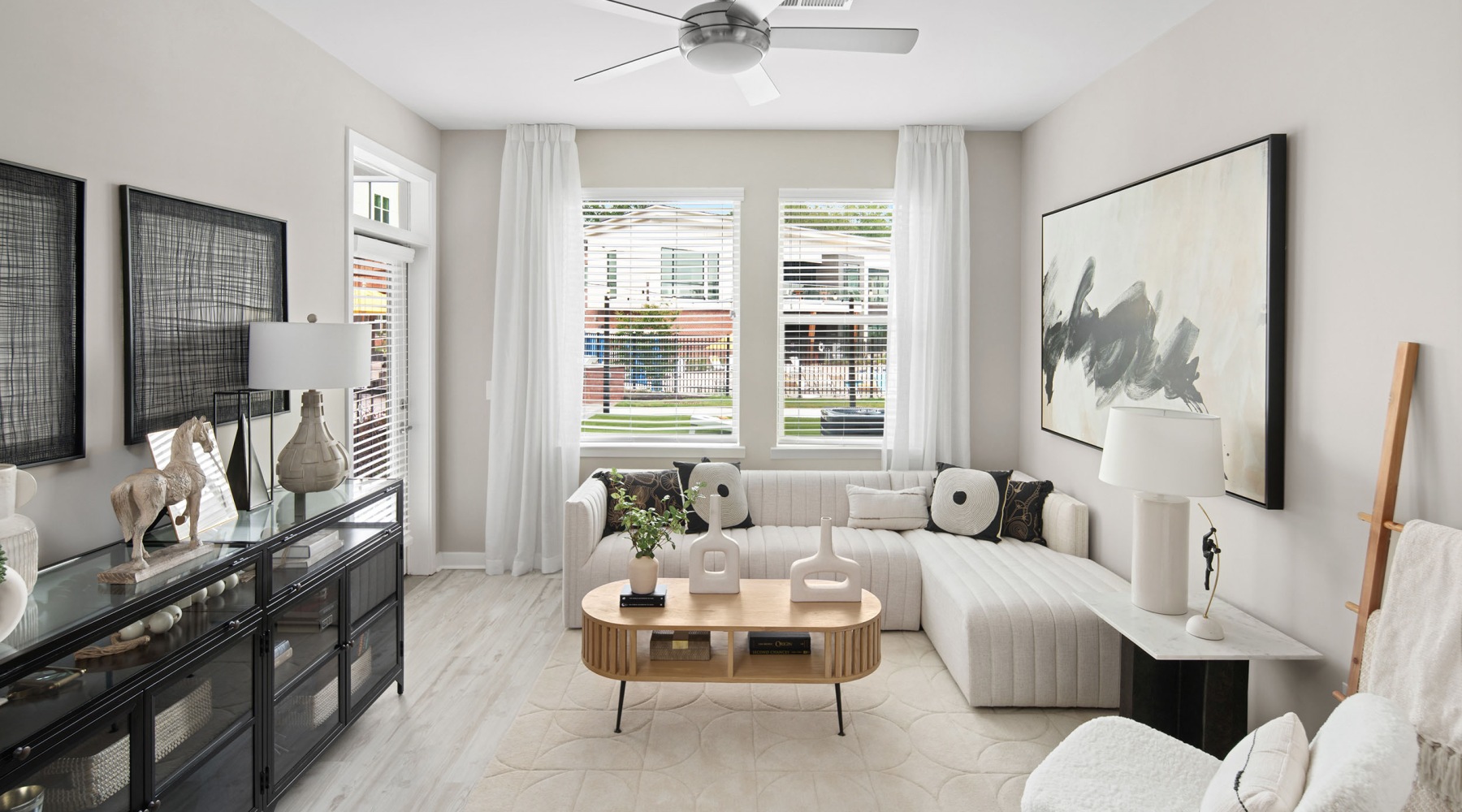 North Raleigh, NC, Apartments Near North Carolina State University - Aventon Nora - Living Room with Wood-Inspired Plank Flooring, Couch, Coffee Table, Side Table, Lamp, Painting, and Ceiling Fan.